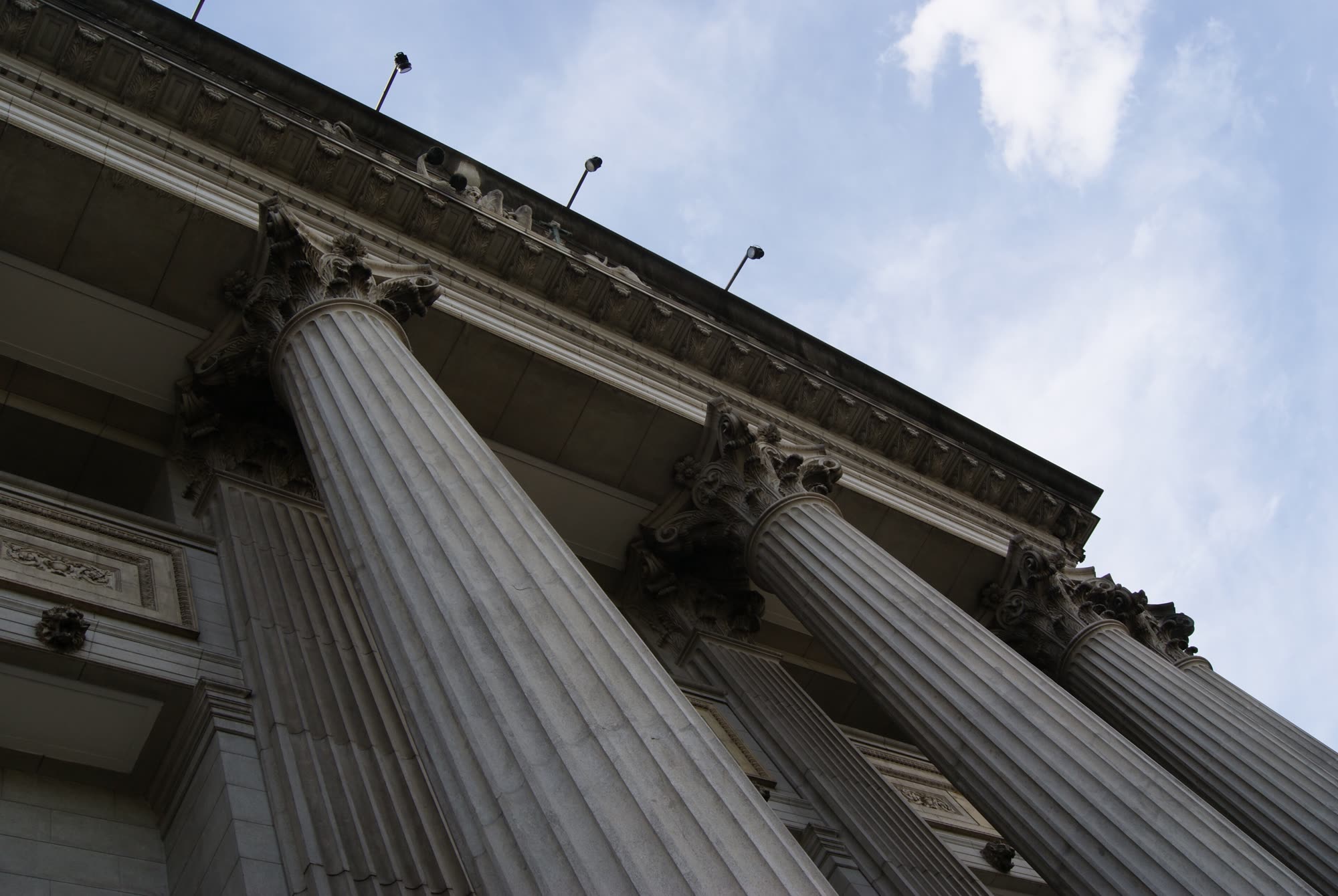 Fluted stone columns of a courthouse rising toward a pale sky