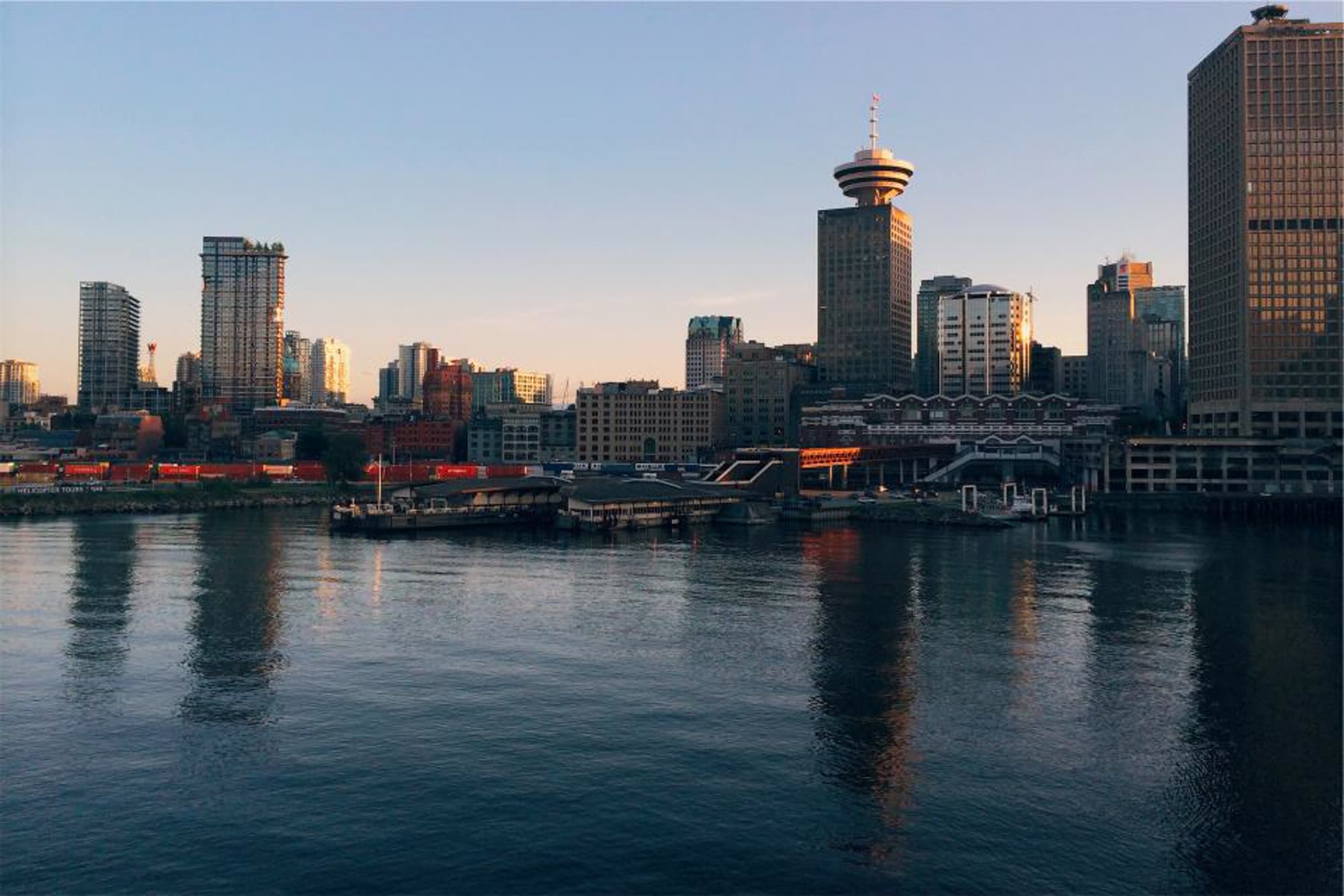 A city skyline at dusk reflected in calm harbor water