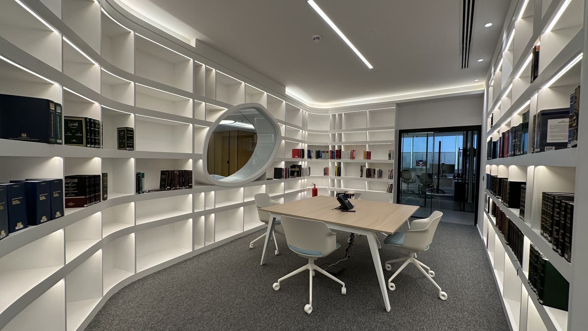 A quiet library meeting room with curved white shelving and a small table