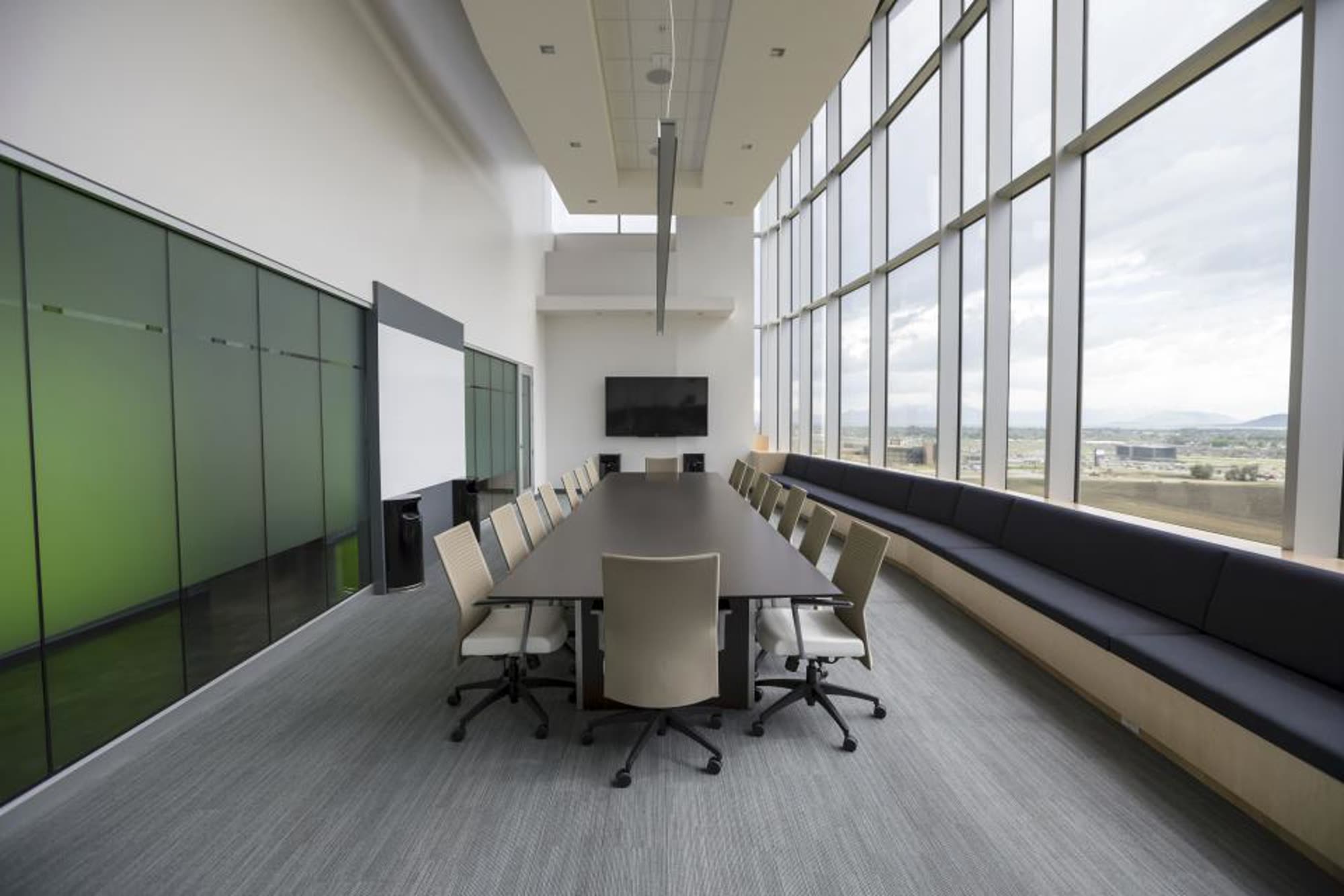 A bright conference room with a long table and a green wall