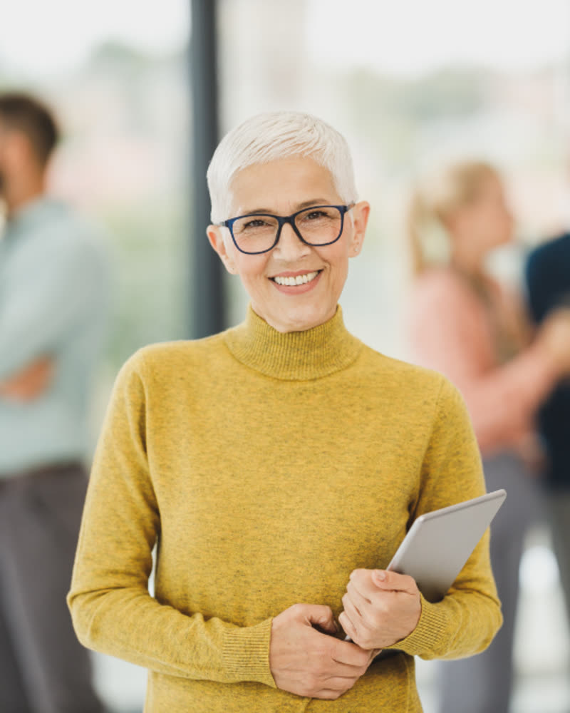 Portrait of Margaret Ellison, a smiling woman with short silver hair and dark-rimmed glasses