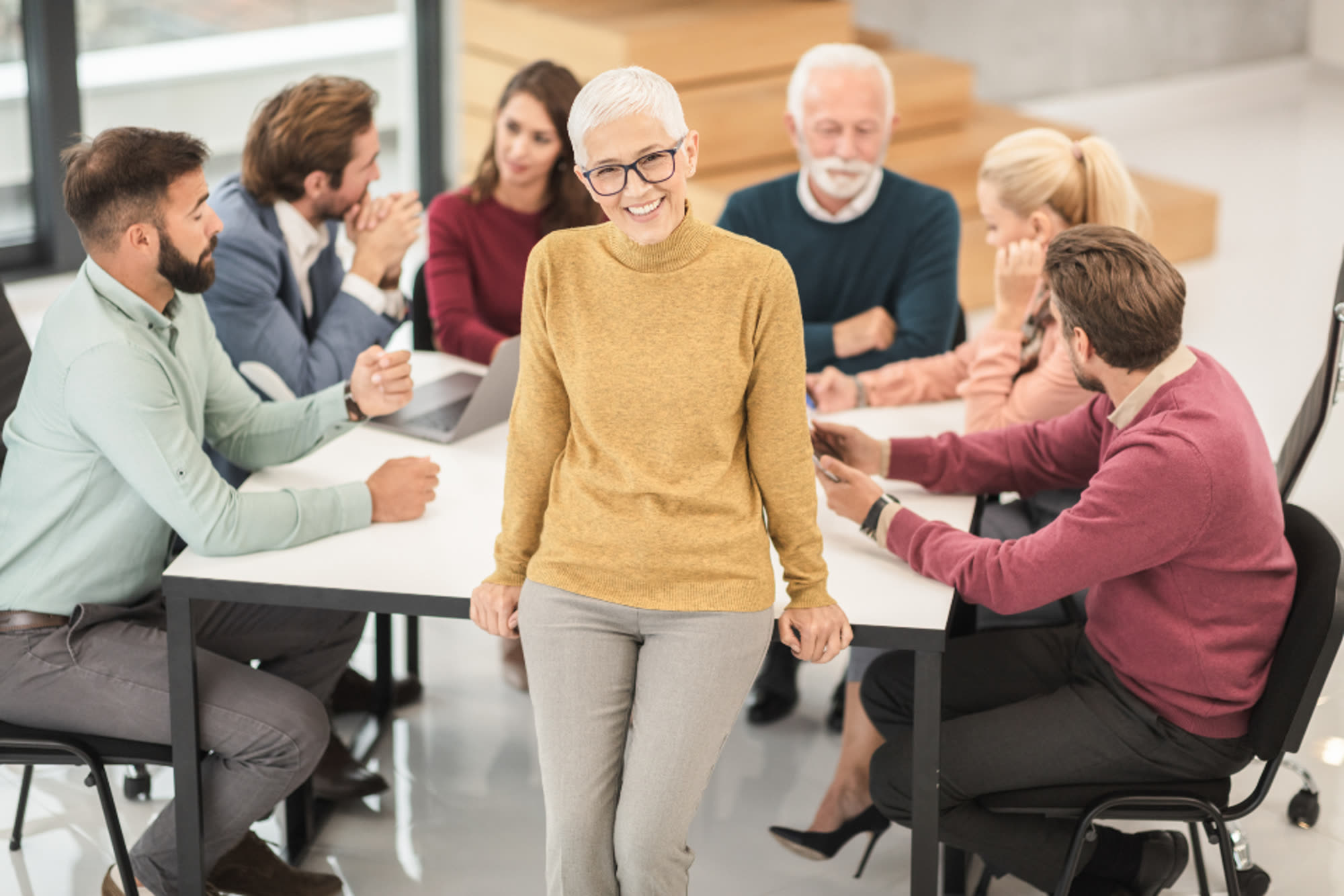 Colleagues gathered around a table in a bright office, discussing a matter
