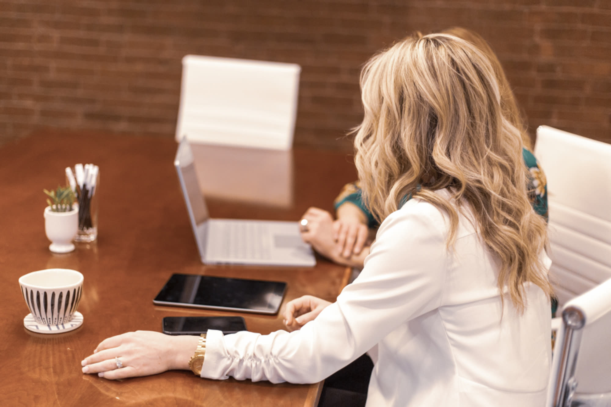 Two colleagues reviewing documents together at a desk with a laptop